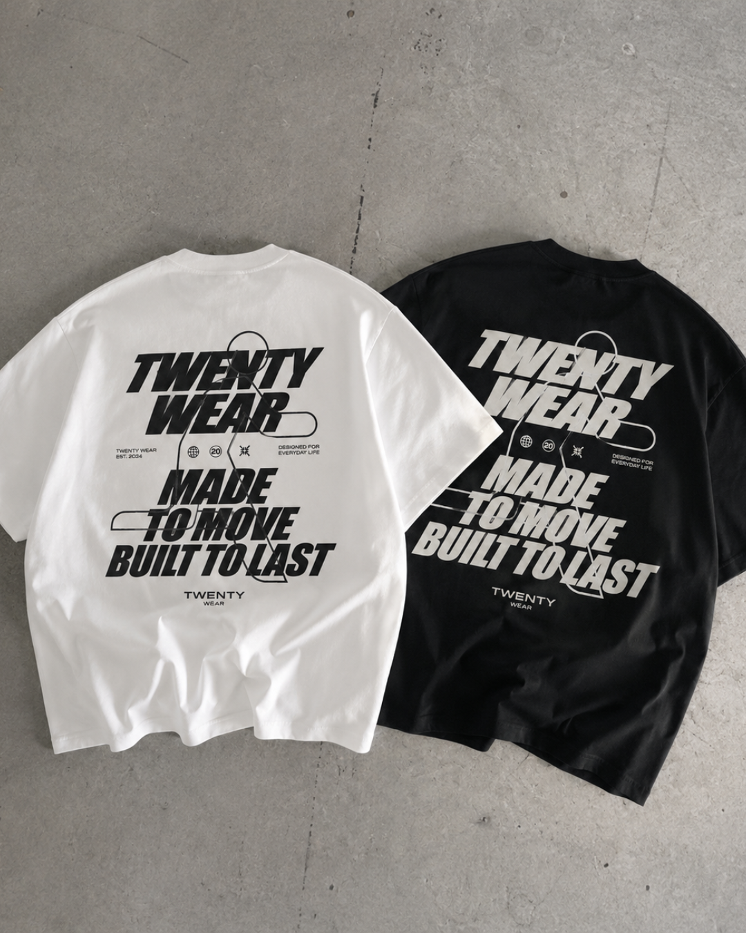 Two oversized short-sleeve T-shirts laid flat on a gray concrete floor, one white and one black, both featuring a large distressed graphic print that reads 'TWENTY WEAR MADE TO MOVE BUILT TO LAST' with small text below.